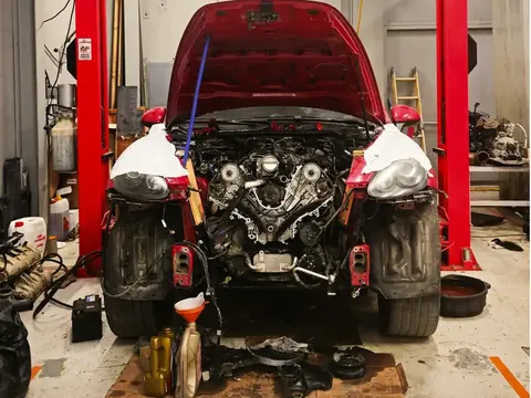 A car on a lift in a repair bay with its hood open.