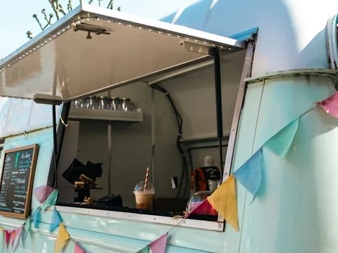 The serving window of a pale blue food truck with bunting.