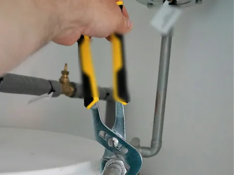 A plumber working on the pipes under a sink.
