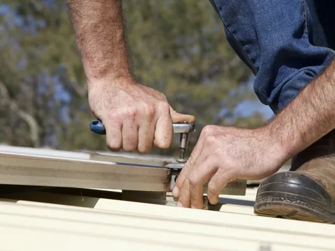 A roofer working on an asphalt shingle roof.